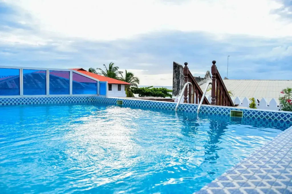 Une piscine bleue bordée d'une terrasse ensoleillée.