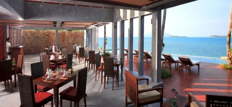 Une salle à manger lumineuse s'ouvre sur une terrasse ensoleillée avec vue sur la mer.
