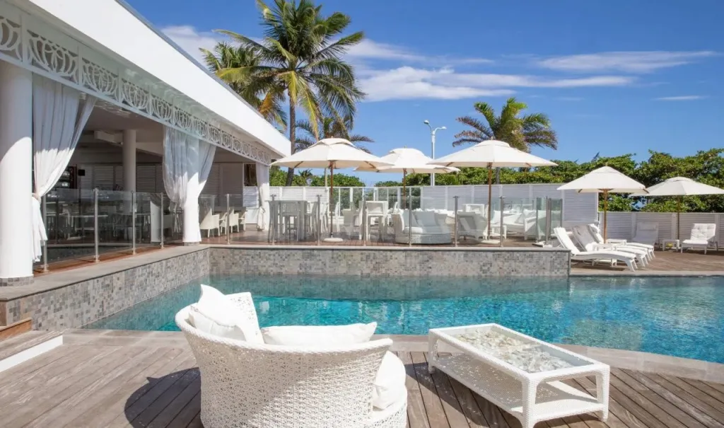 Une piscine bordée de chaises longues et de parasols blancs offre un espace de détente ensoleillé.