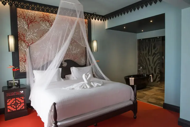 Une chambre à coucher avec un lit à baldaquin et une baignoire visible à travers une ouverture.