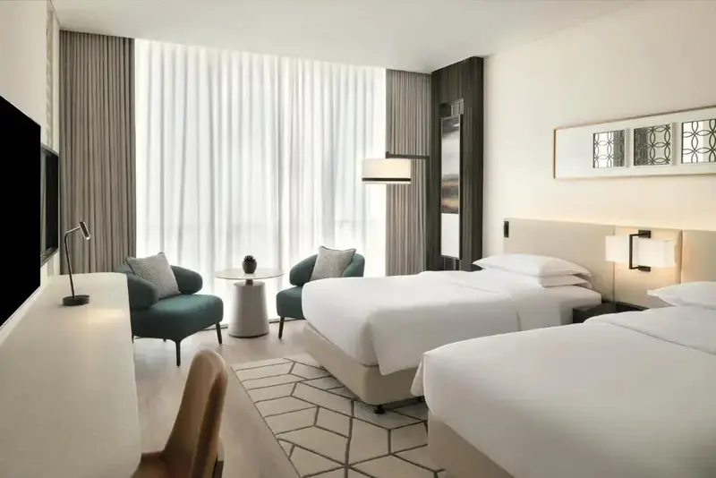 Une chambre lumineuse avec deux lits simples et un coin salon.