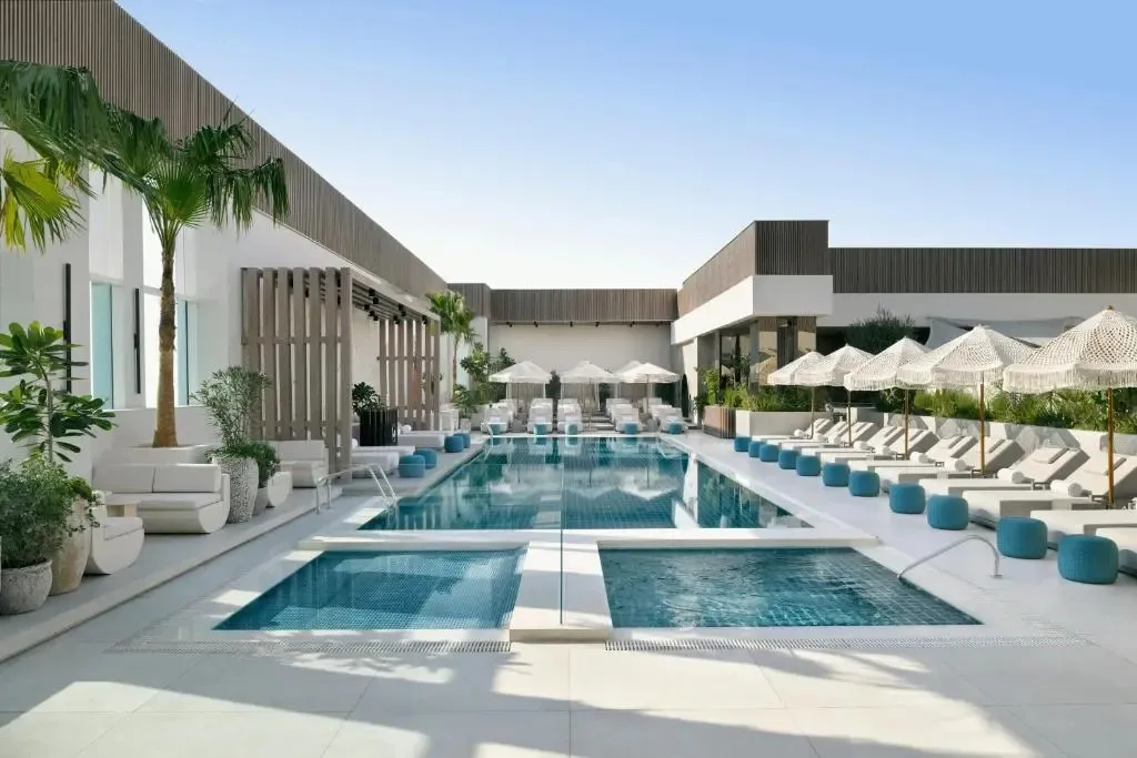 Une piscine rectangulaire bordée de transats sous des parasols.
