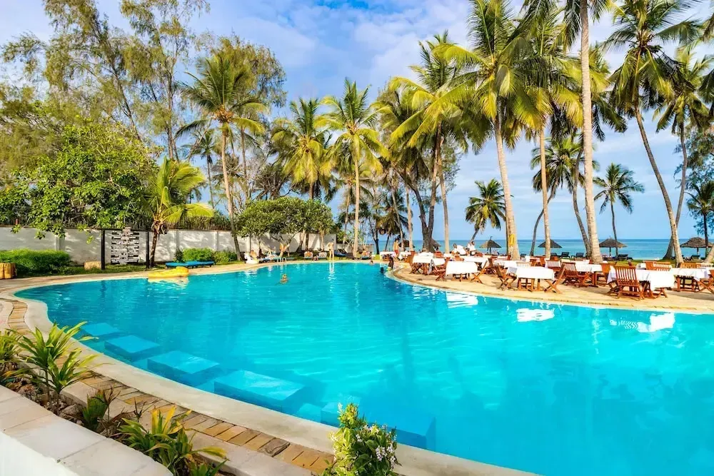 Une piscine turquoise bordée de palmiers et de transats.