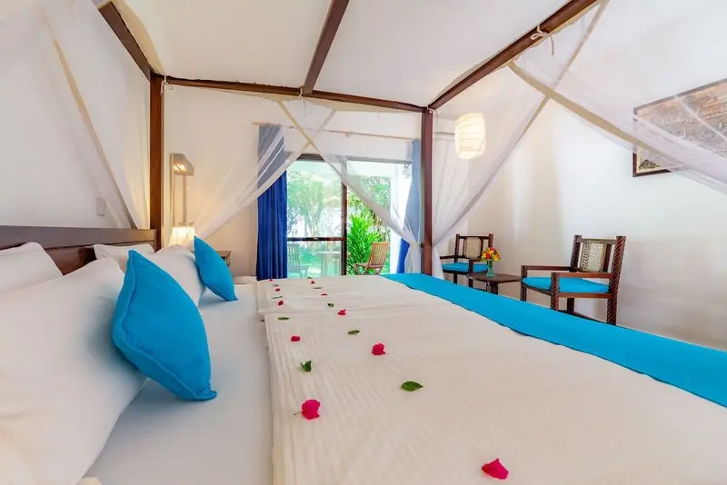 Une chambre lumineuse avec un lit décoré de pétales de fleurs et deux fauteuils.