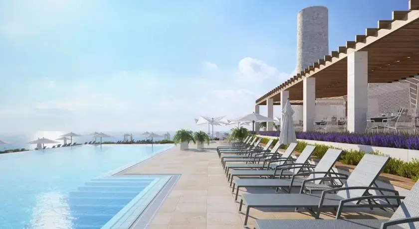 Transats alignés au bord d'une piscine à débordement avec vue sur la mer.