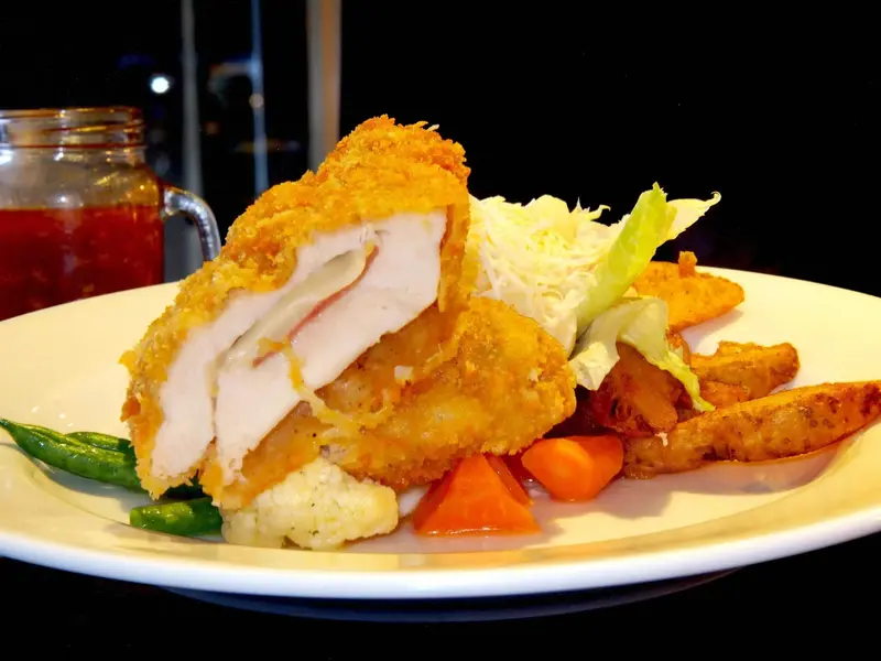 Assiette généreuse avec une portion de viande panée, des légumes et des frites.