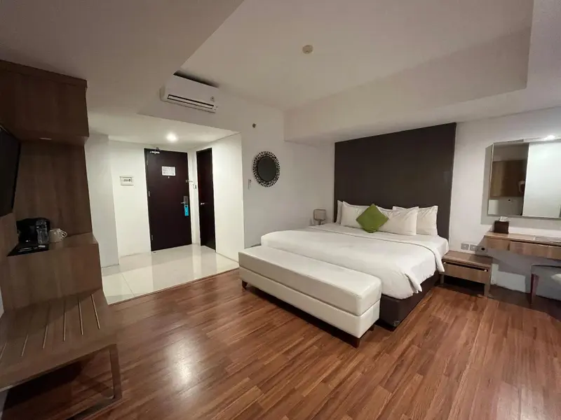 Une chambre spacieuse avec un grand lit et un téléviseur.