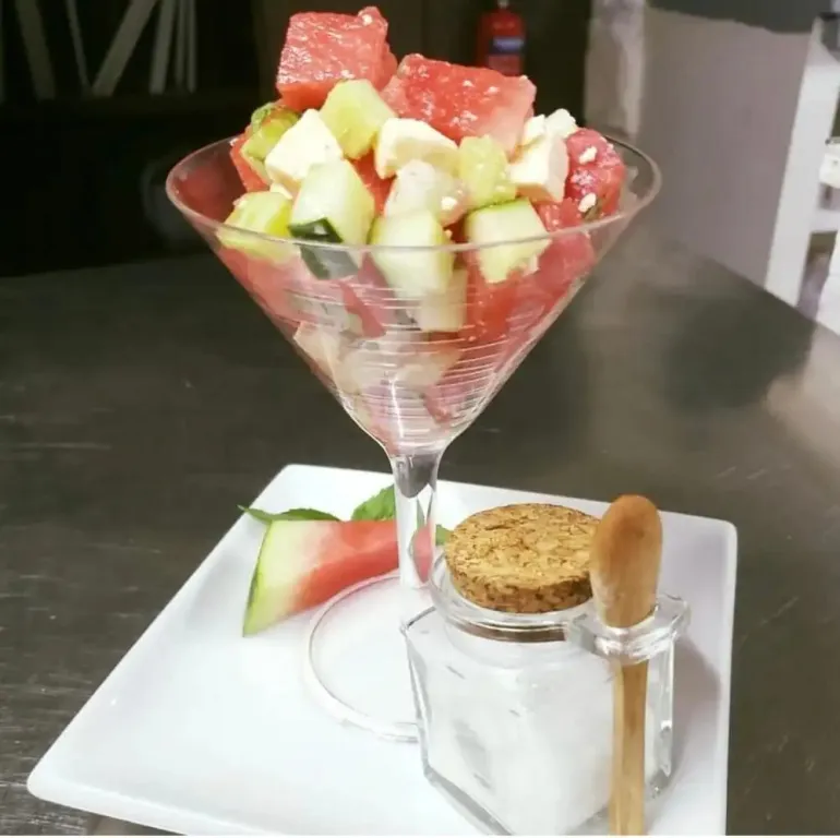 Salade de fruits frais présentée dans un verre à cocktail sur une assiette blanche.