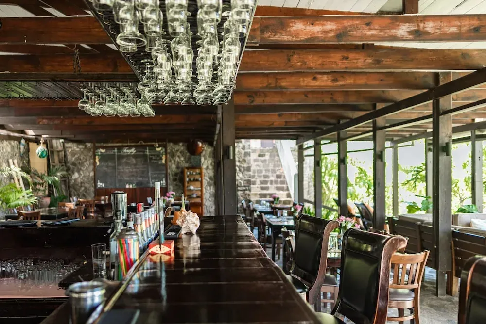 Un comptoir de bar en bois sombre avec des verres suspendus au-dessus.