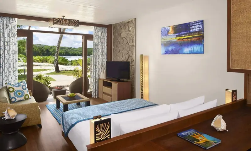 Une chambre lumineuse s'ouvre sur une vue verdoyante et la mer.