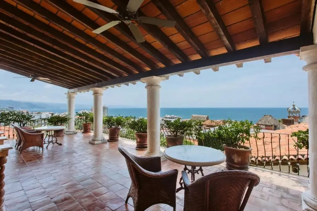 Terrasse ombragée avec mobilier en osier donnant sur la mer.