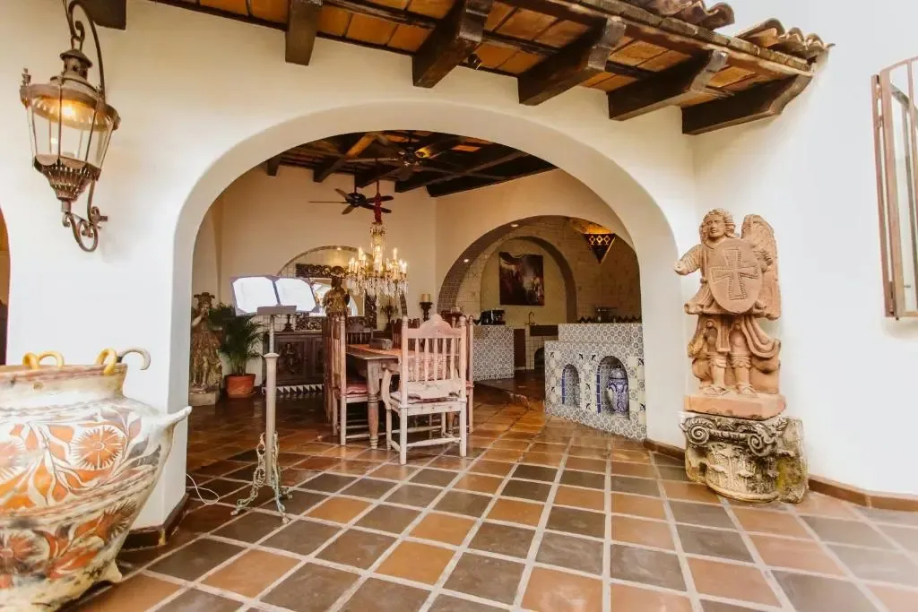 Une salle à manger intérieure s'ouvre sur un espace décoré d'arches et de statues.