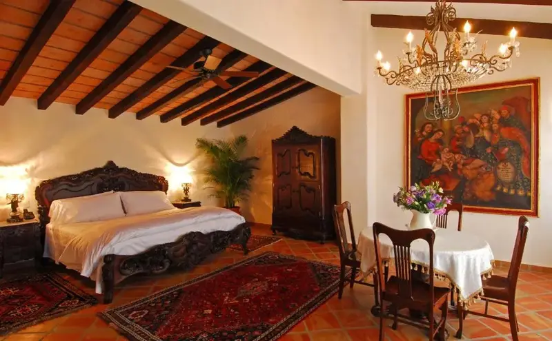 Une chambre à coucher spacieuse avec un grand lit à baldaquin et un coin repas.
