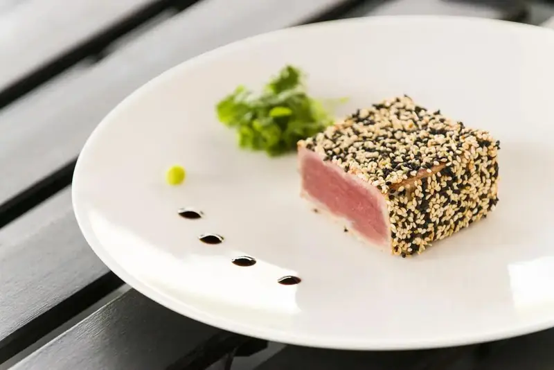 Un plat de poisson enrobé de graines est présenté sur une assiette blanche.