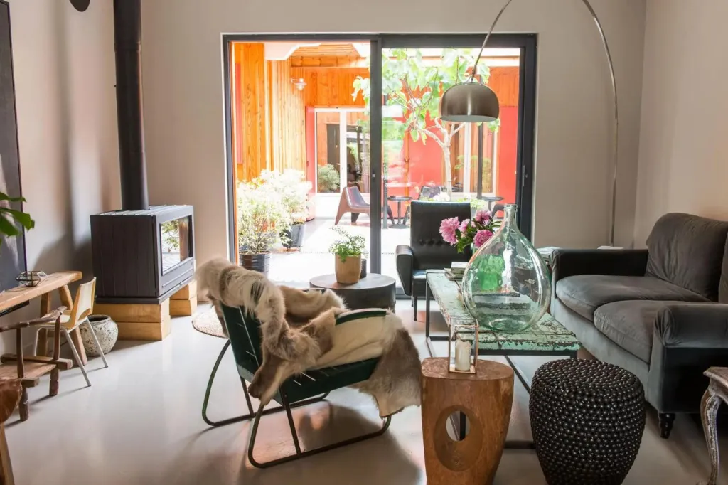 Un salon lumineux s'ouvre sur une terrasse ombragée par des arbres.