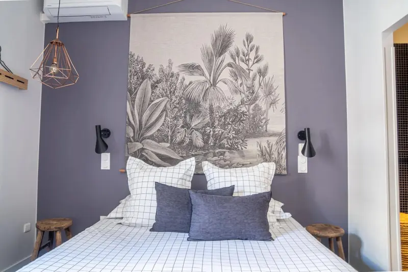 Une chambre à coucher avec un grand motif végétal au-dessus du lit.