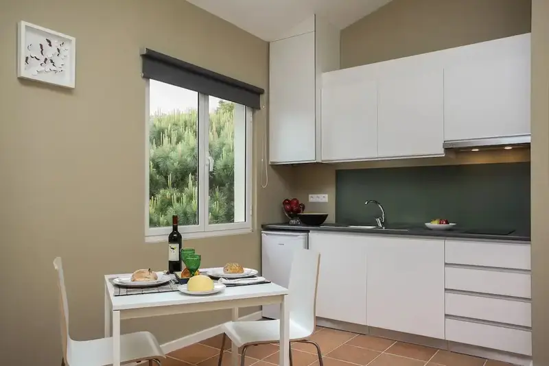 Une kitchenette lumineuse avec une table à manger près d'une fenêtre.
