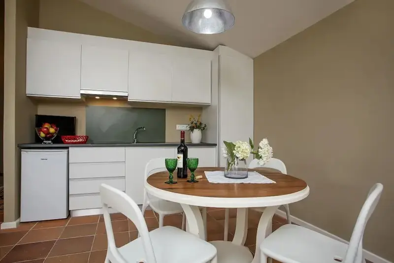 Une kitchenette et une table ronde avec des chaises dans une pièce lumineuse.