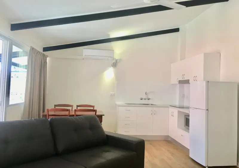 Espace de vie lumineux avec canapé, table à manger et cuisine équipée.