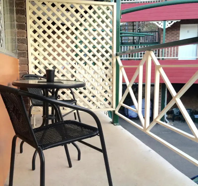 Une table et des chaises noires se trouvent sur une terrasse ensoleillée.