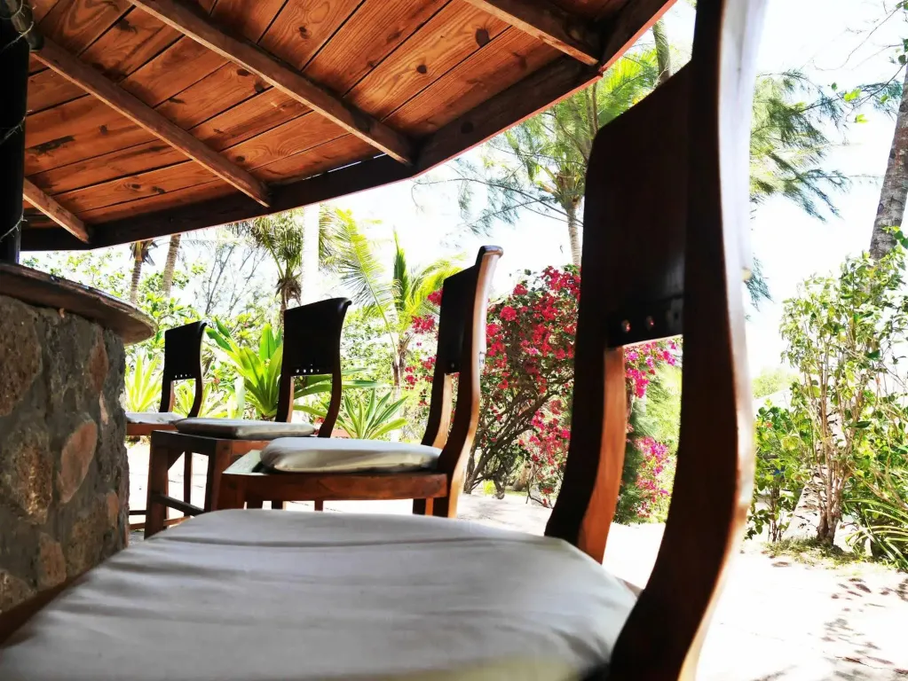 Terrasse ombragée avec mobilier en bois donnant sur une végétation luxuriante.