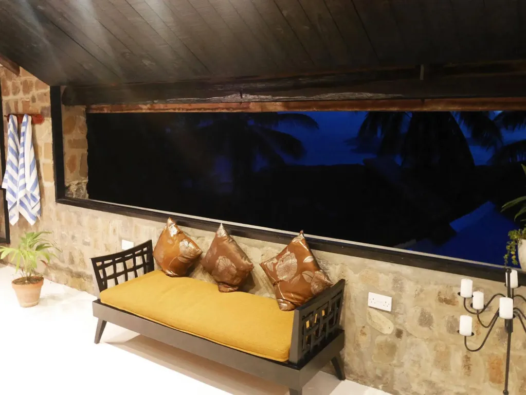 Un espace de détente extérieur avec un canapé et des coussins face à une ouverture sombre.