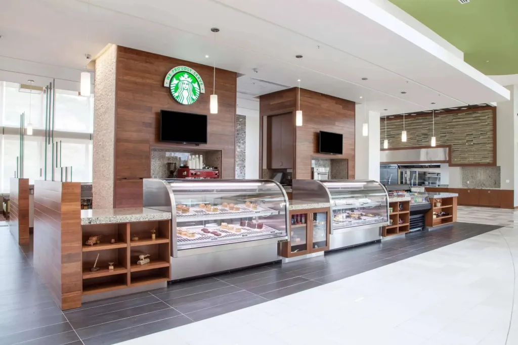 Un comptoir de vente présente des pâtisseries et des boissons dans un espace lumineux.