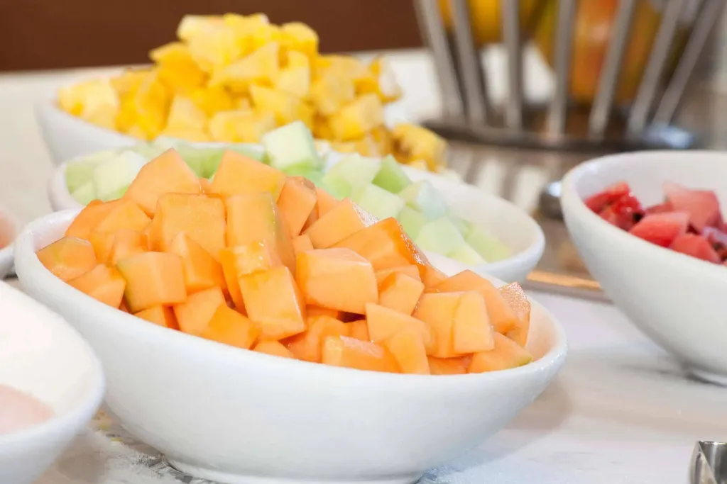 Des saladiers remplis de fruits frais coupés sont présentés sur un comptoir.