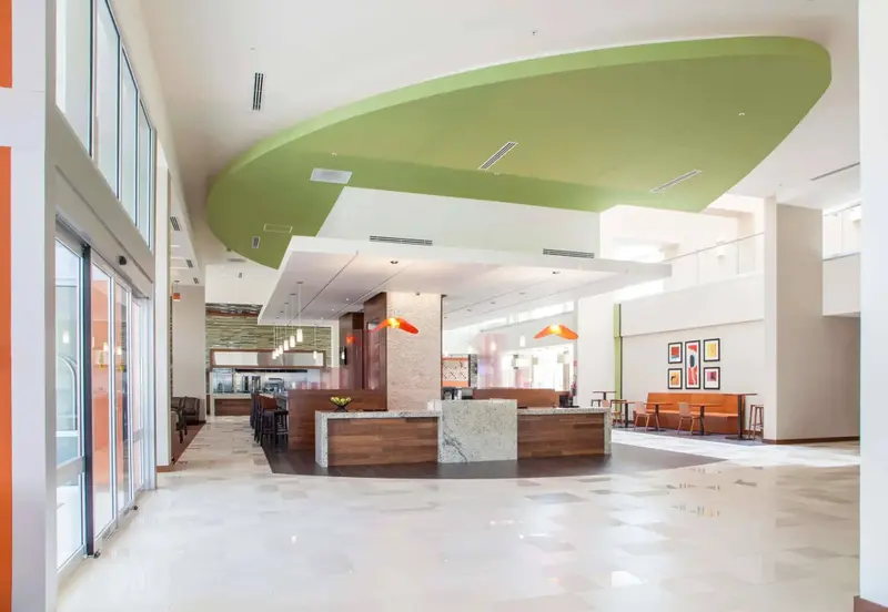 Vaste hall d'accueil lumineux avec un comptoir de réception central et des espaces de détente.