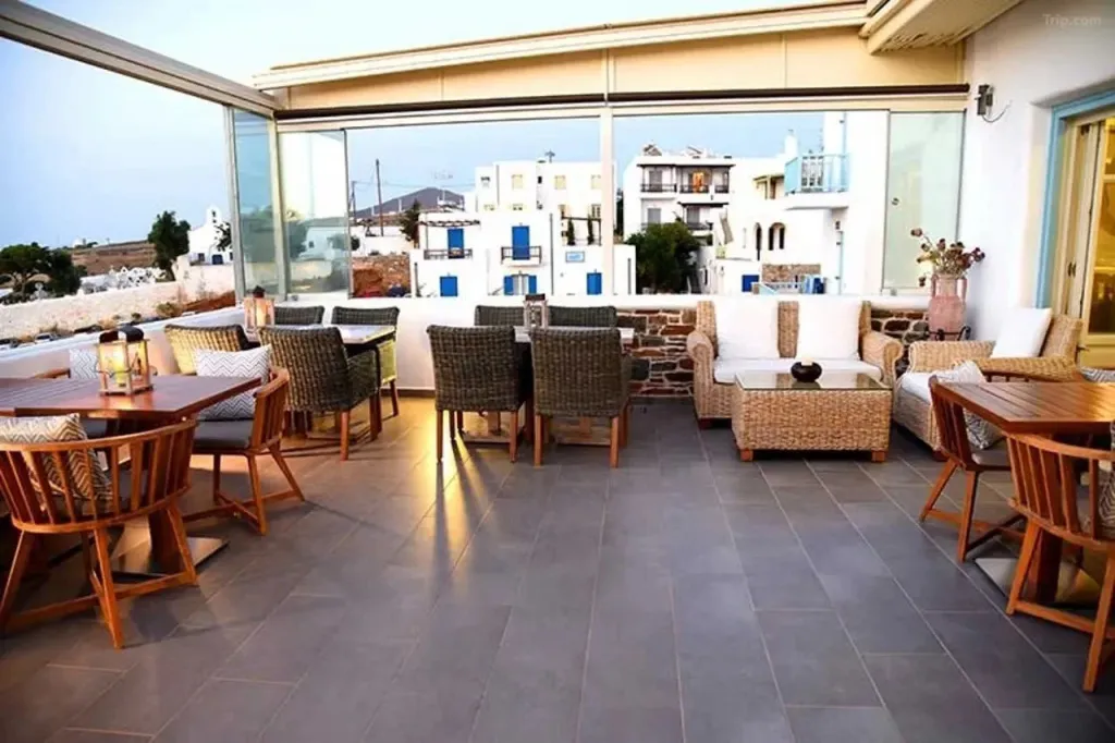 Espace de détente extérieur avec tables et canapés près d'une baie vitrée.