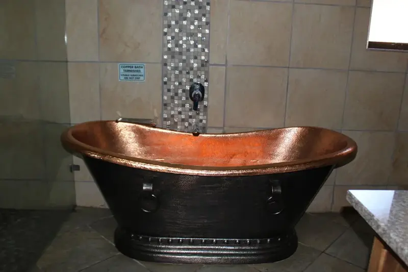 Une baignoire en cuivre est l'élément central d'une salle de bain carrelée.