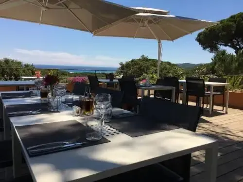 Tables dressées sur une terrasse ensoleillée avec vue sur la mer.