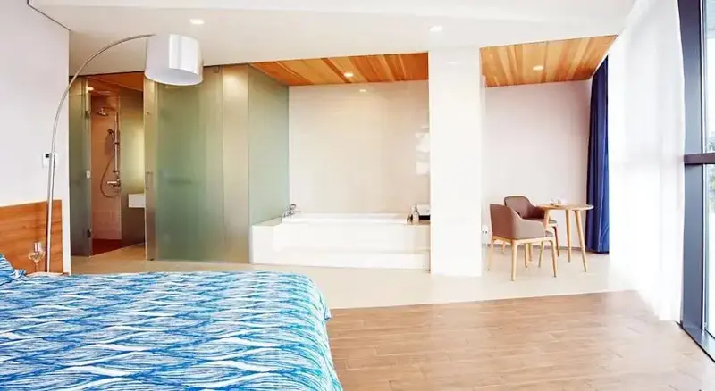 Une chambre spacieuse avec un lit et une baignoire intégrée.