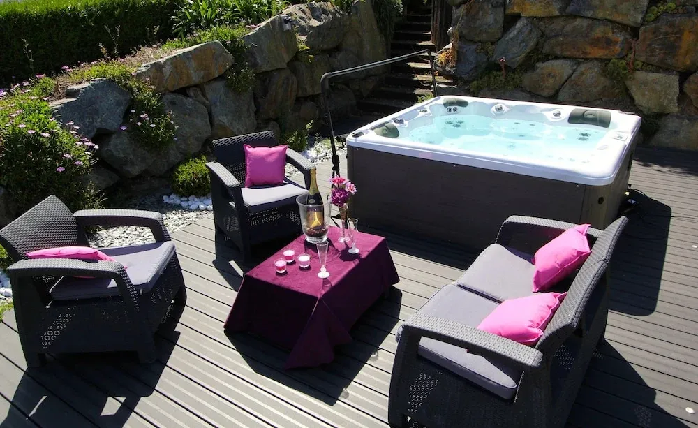Espace extérieur aménagé avec un jacuzzi et des fauteuils.