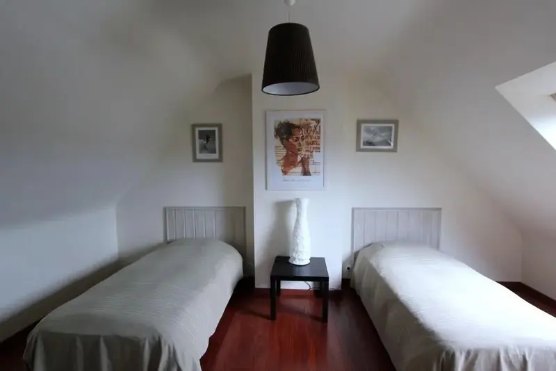 Une chambre lumineuse avec deux lits simples et une décoration sobre.