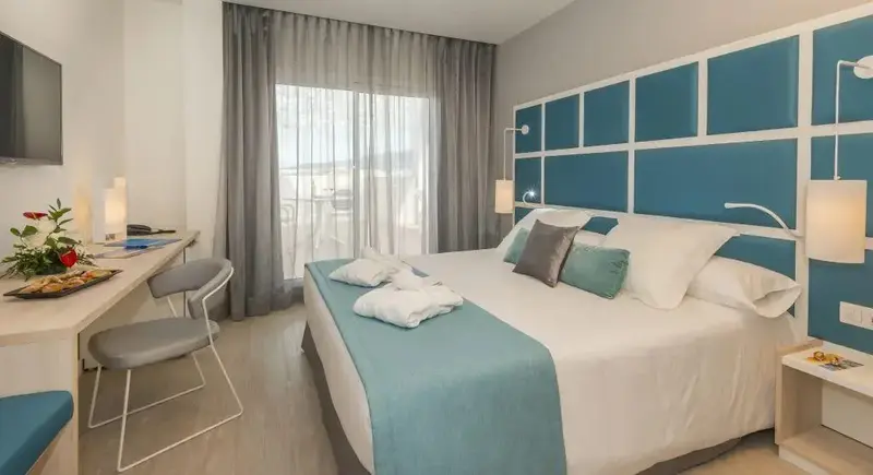 Une chambre lumineuse avec un grand lit et un bureau.