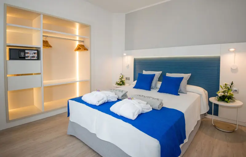 Une chambre lumineuse avec un grand lit recouvert d'une courtepointe bleue et de coussins.