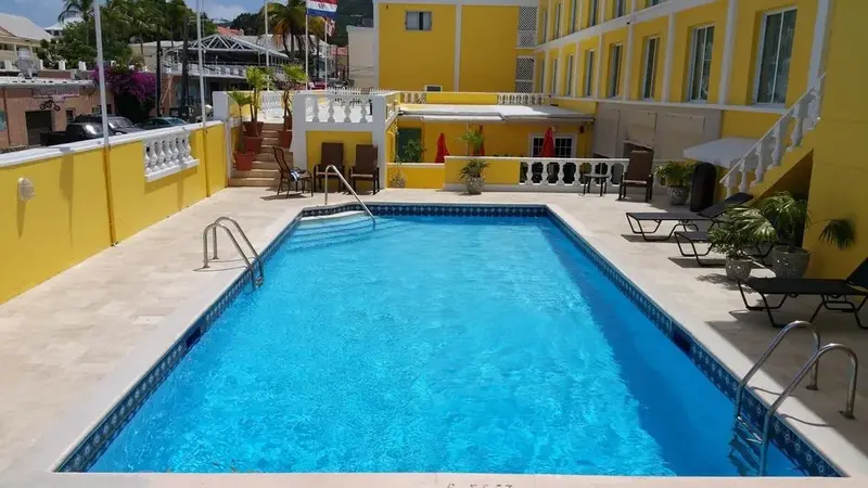Une piscine rectangulaire entourée d'une terrasse ensoleillée avec des chaises longues.