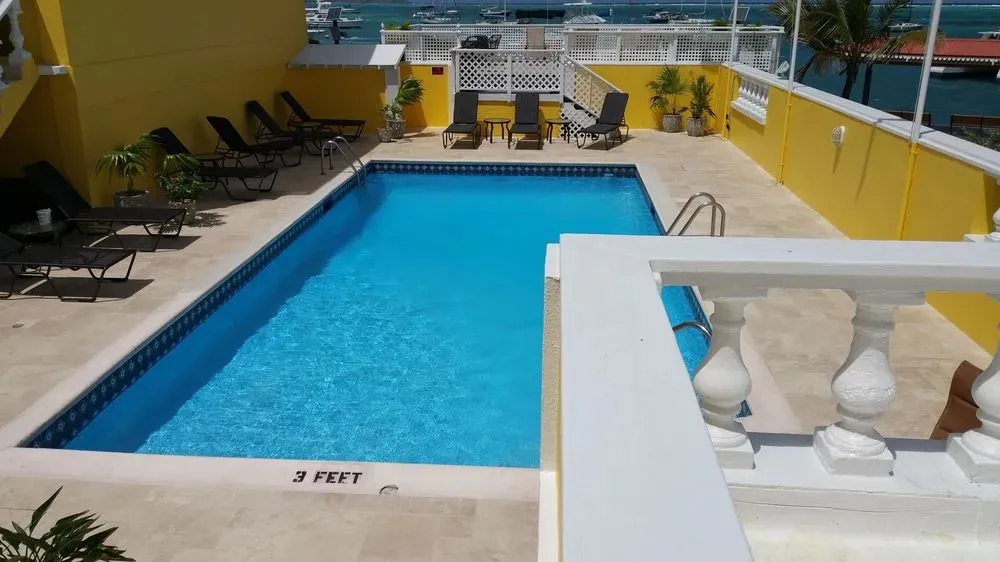 Une piscine rectangulaire entourée de chaises longues sur une terrasse ensoleillée.