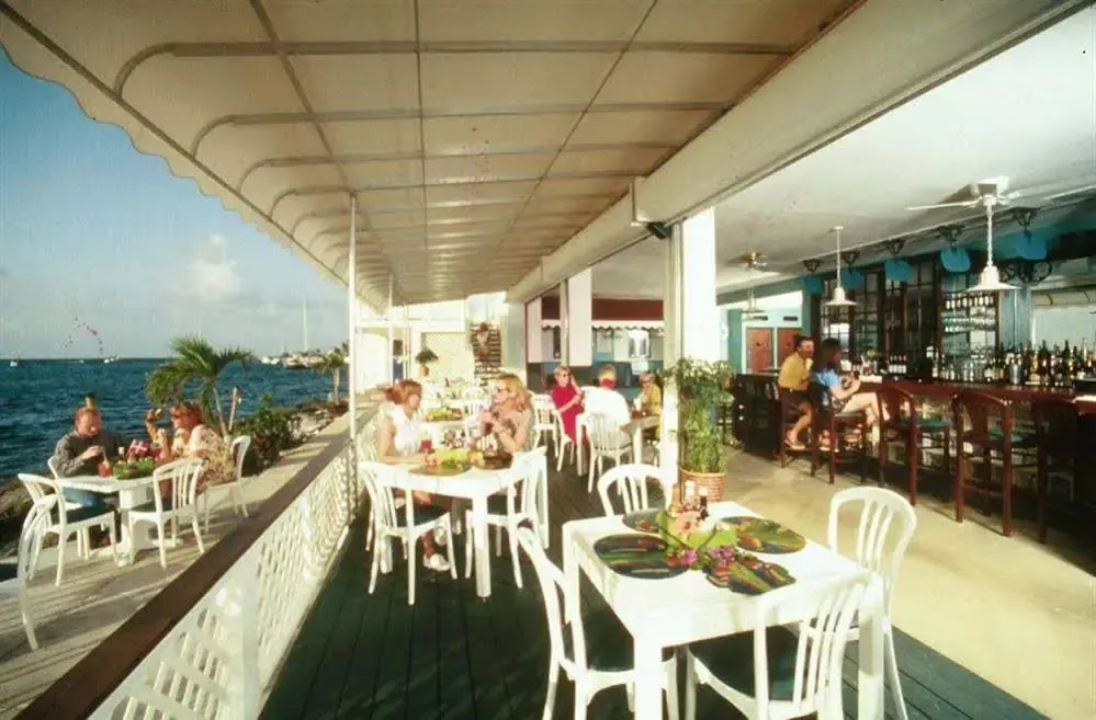 Une terrasse abritée accueille des clients attablés face à la mer.