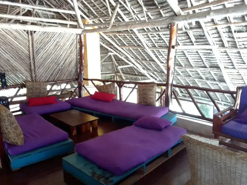 Espace de détente extérieur avec des coussins violets et des assises en bois.