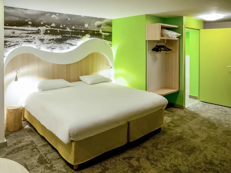 Une chambre lumineuse avec un grand lit et un mur décoré d'une scène marine.