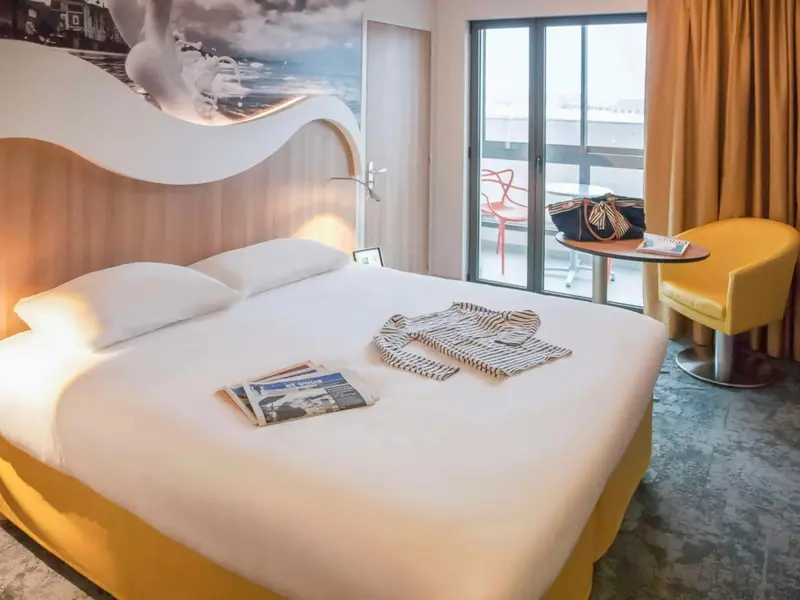 Une chambre lumineuse avec un grand lit et un balcon.