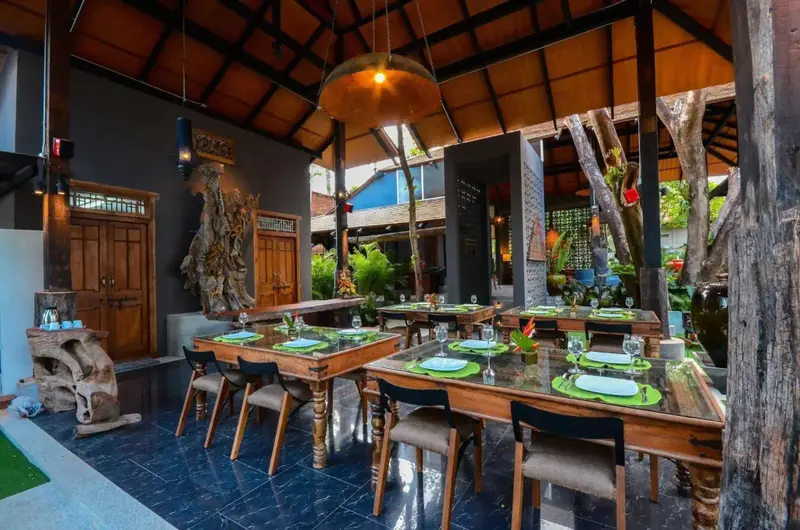Une salle à manger extérieure avec des tables dressées et une décoration florale.