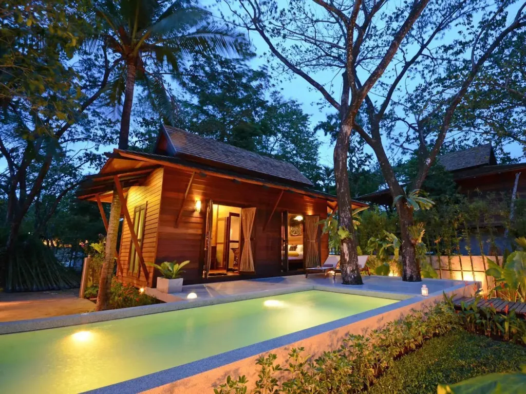 Une petite maison en bois avec une piscine privée et une végétation luxuriante.
