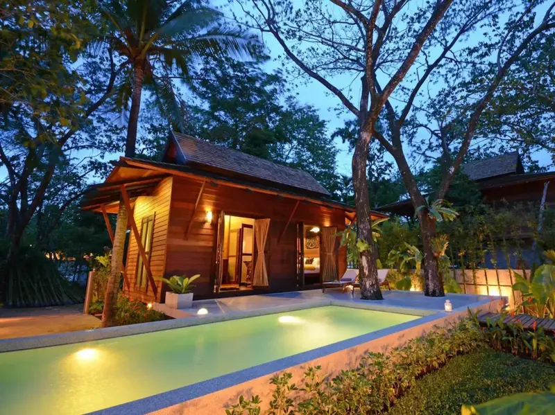 Une petite maison en bois avec une piscine privée et une végétation luxuriante.