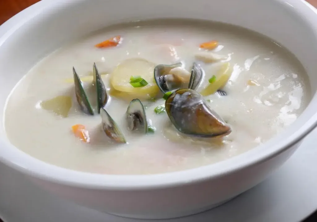 Une soupe de fruits de mer crémeuse est servie dans un bol blanc.