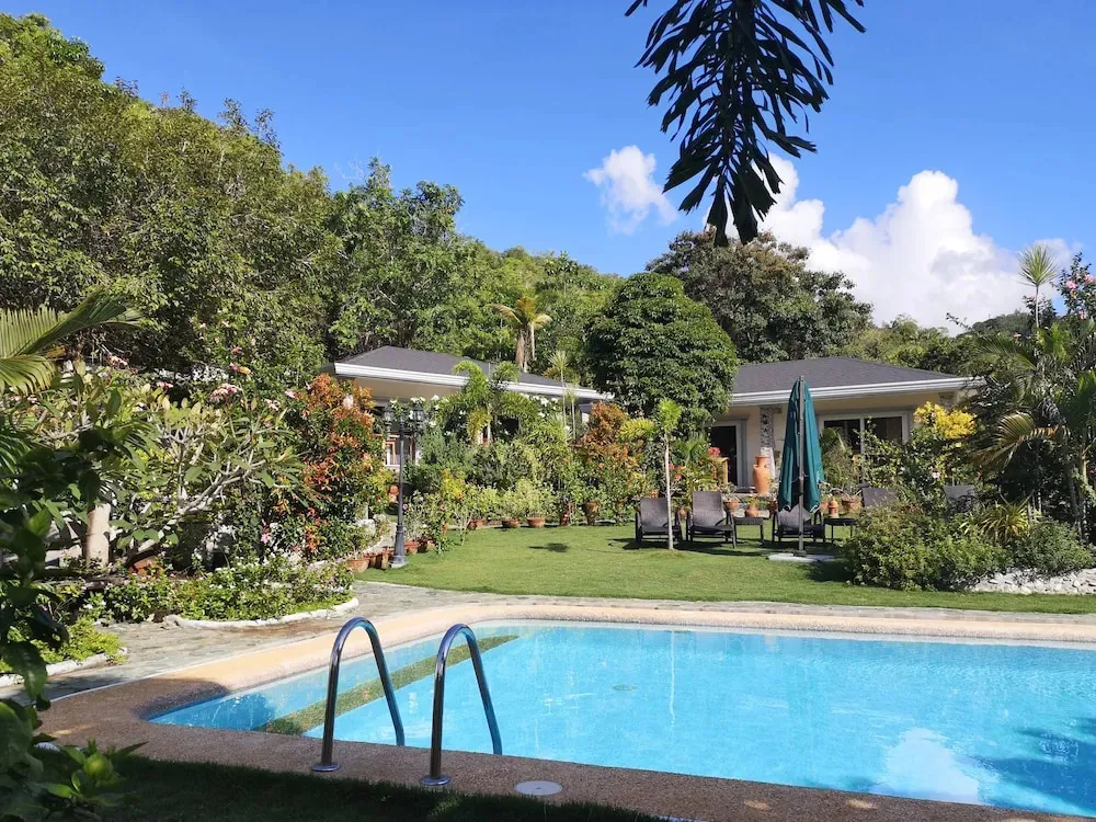 Une piscine turquoise bordée d'une pelouse verdoyante et de végétation luxuriante.