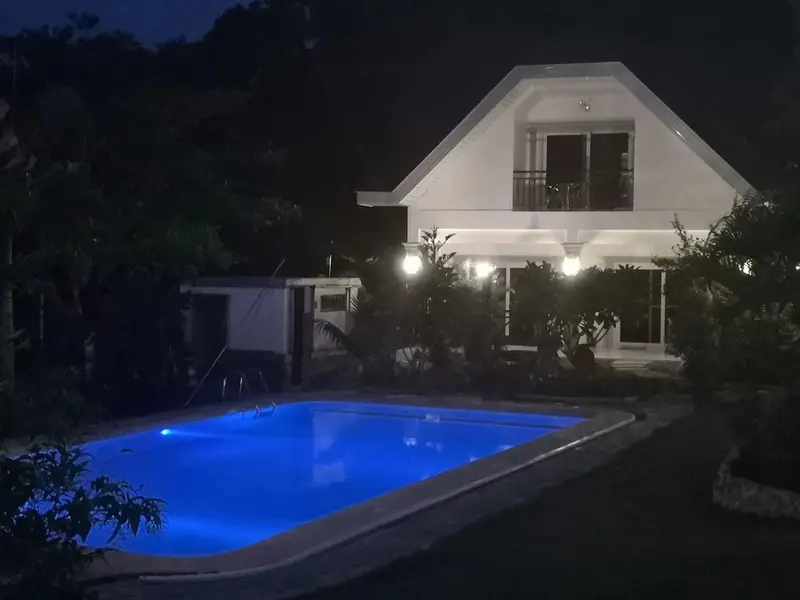 Bâtiment éclairé avec une piscine au premier plan.
