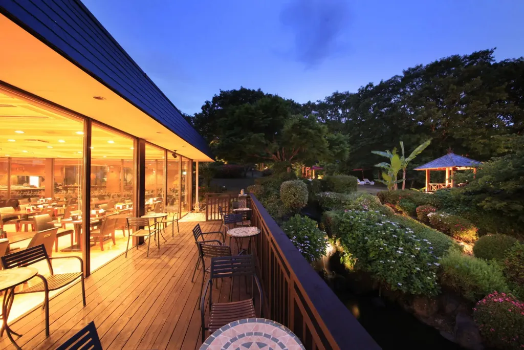 Terrasse lumineuse donnant sur un jardin soigné au crépuscule.